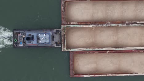 Barge-pushing-hoppers-laden-with-Sand-sailing-on-Ohio-river,-top-down-close-up