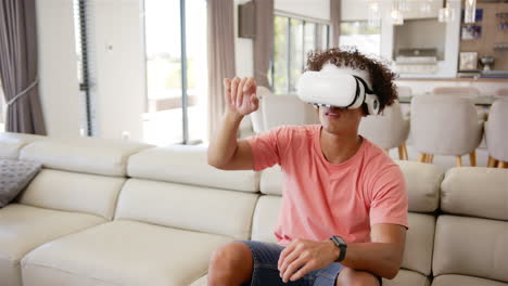 A-young-biracial-man-with-curly-hair-sits-on-couch,-copy-space