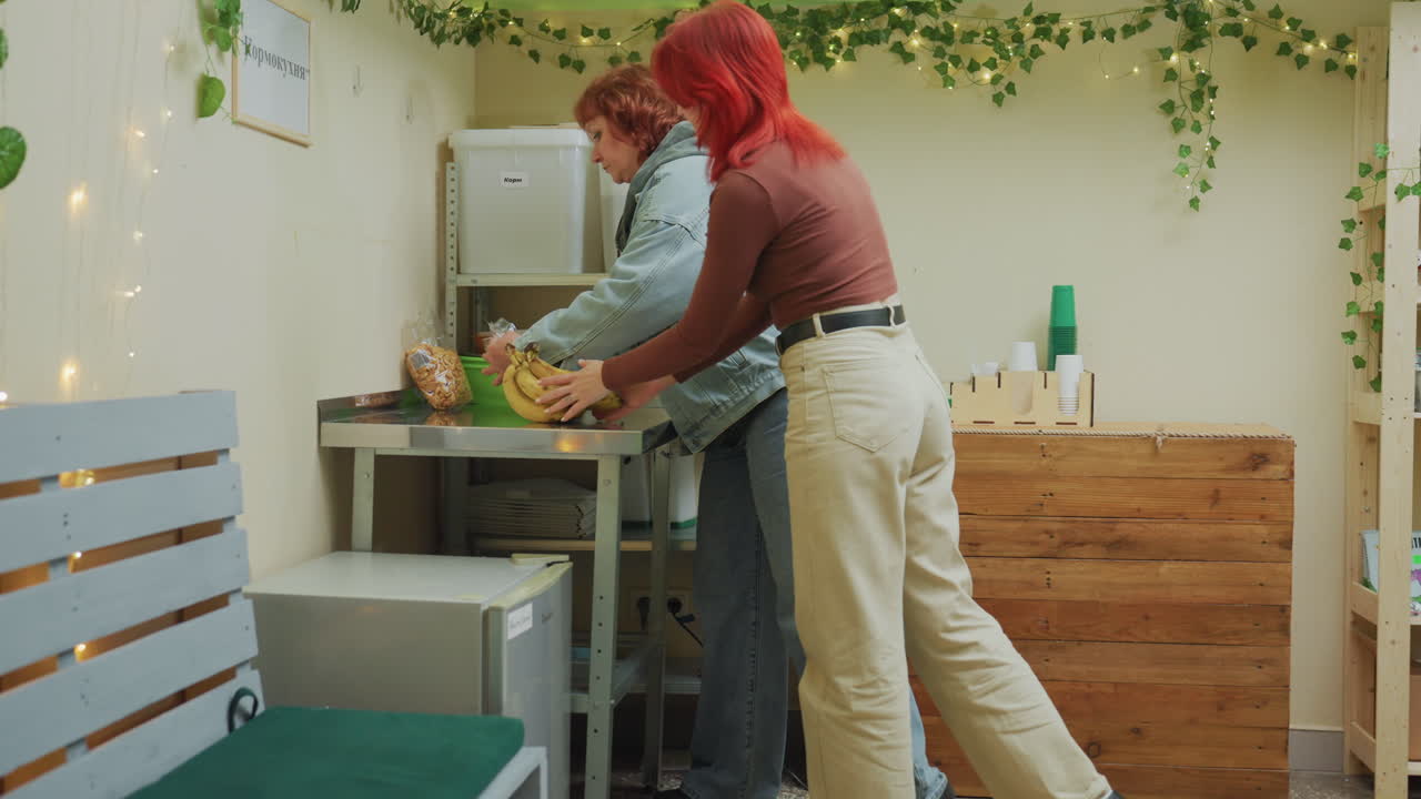 Zonnige serre vol planten, witte vrienden die schalen en vetplanten op een houten tafel rangschikken, lichtslingers, groene bankkussens, met klimplanten bedekte muren, casual denim en roestkleurige outfits, coöperatieve styling