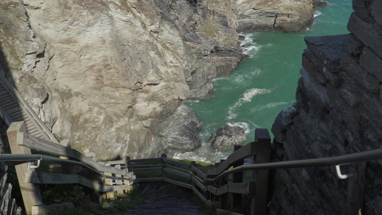 Close up view of one of the Tintagel Castle is a medieval fortification located on the peninsula of Tintagel. View of the steep steps that leads to the bottom of the hill, waves hitting the coast