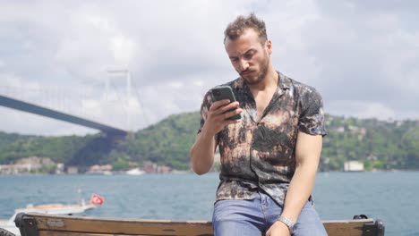 Thoughtful-young-man-texting-on-the-phone.