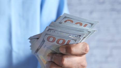 persona que sostiene una pila de nosotros cien billetes de dólar