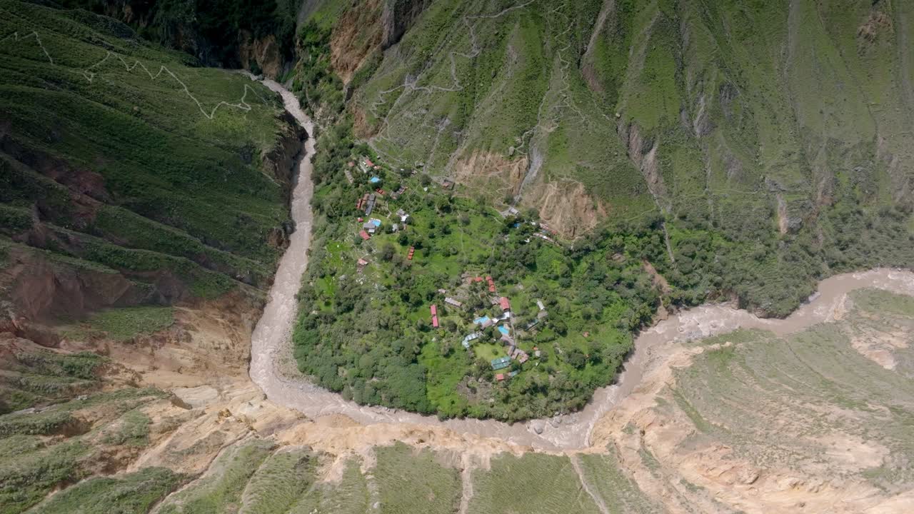 High-altitude drone shot showcasing the vast landscape of Sangalle Oasis, with the river winding through the Colca Canyon and trekking paths visible in the distance, creating a breathtaking view.