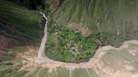 high-altitude drone shot showcasing the vast landscape of sangalle oasis, with the river winding through the colca canyon and trekking paths visible in the distance, creating a breathtaking view.