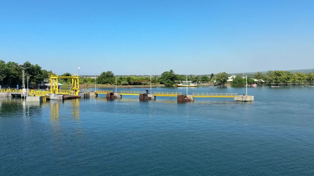 Struttura di diga gialla su un fiume calmo sotto un cielo azzurro e limpido