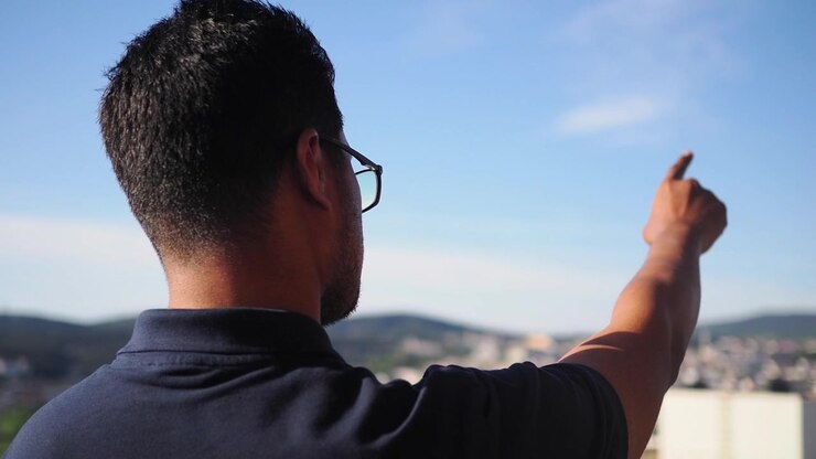 Man Pointing at Distant Cityscape from Rooftop