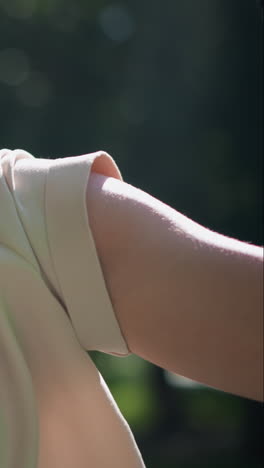 primer plano de una mujer flexionando su brazo en una postura fuerte y confiada, usando guantes de motociclista, con un fondo natural verde y borroso, su expresión y postura transmiten empoderamiento