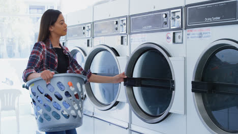 mujer poniendo ropa en la lavadora 4k