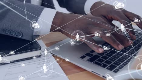animation of network of icons over african american businessman using laptop
