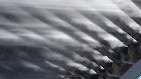 vertical format: back lit water falls in rain drops from hydro dam