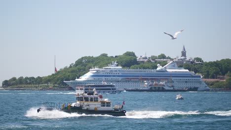 a large cruise ship is docked in the harbor with smaller boats in the foreground.