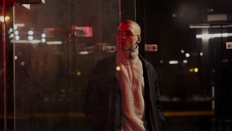 night portrait of a man with glasses in an urban setting with red reflections