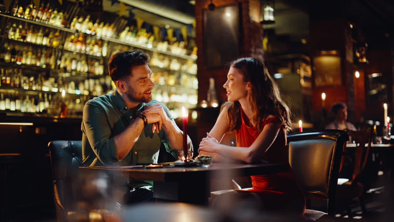 Coppia felice di innamorati che chiacchiera seduta in un pub in un'atmosfera accogliente. Coppia sorridente che flirta