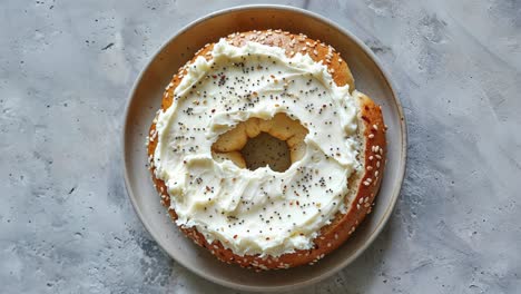 a bagel with cream cheese, sesame seeds and poppy seeds on a plate