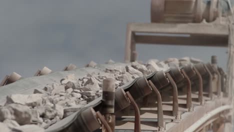 conveyor belt of a stone crusher carrying rocks to be crushed with a sky with clouds in the background