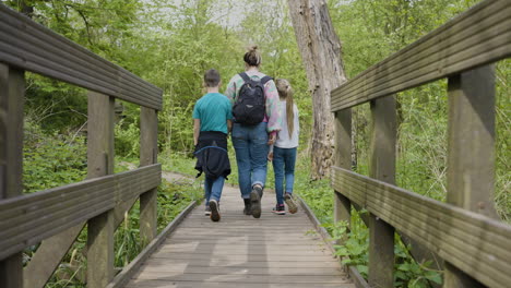 family hiking on wooden bridge in a woodland