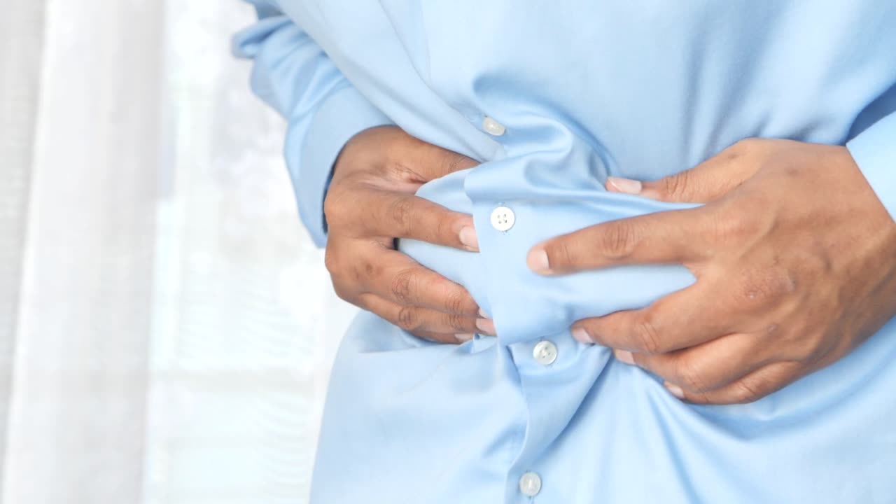 hombre sosteniendo su estómago en dolor