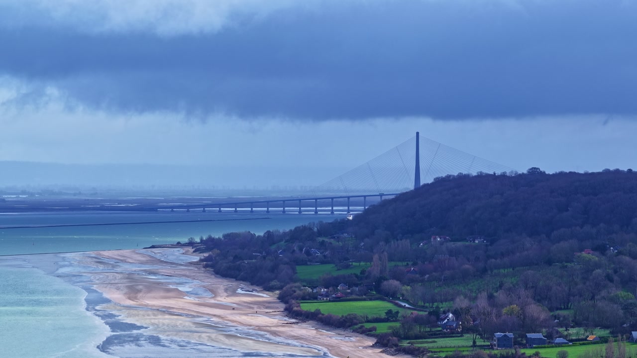 Cloudy morning view of Plage de Pennedepie and distant Normandy bridge