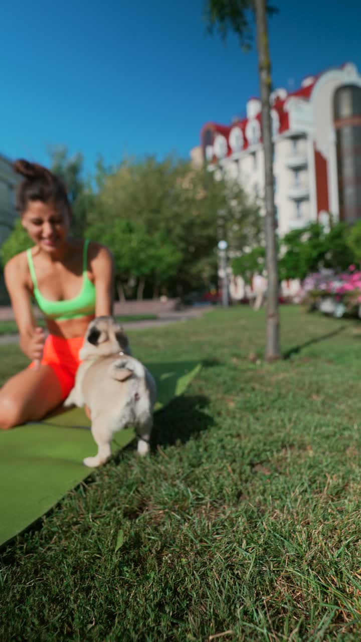 mujer haciendo yoga con su pug en un parque