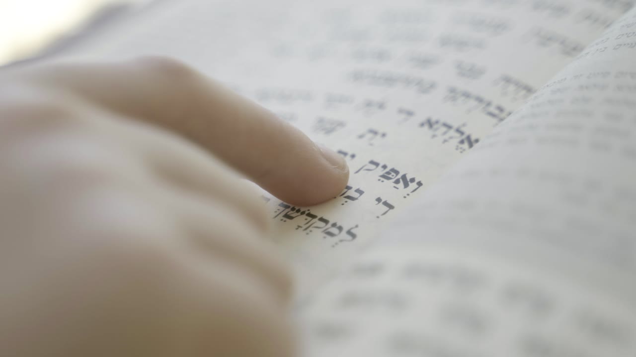 A boy reading a Hebrew holy book, Follows the reading with his finger, Jewish Book of Prayer BookSuper close up shote