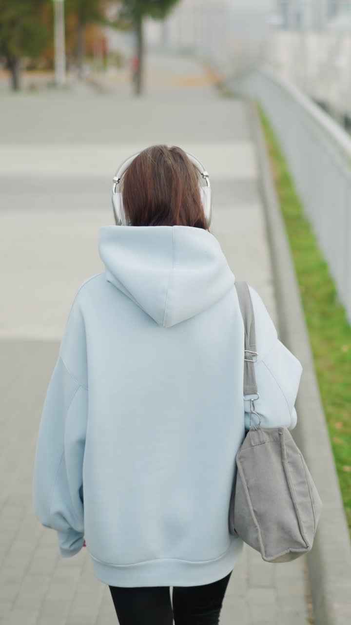 Lady walking along street with blurred view of bridge, river, and street lights in background, serene outdoor setting, casual walk, peaceful environment, cityscape with nature