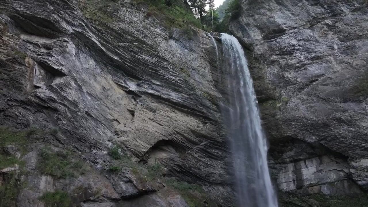 Utsikt over en majestetisk foss i Berschis, St. Gallen, Sveits, som fosser gjennom frodig grønt og steinete klipper, omgitt av naturlig skjønnhet og rolig natur