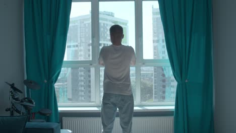 man looking out window at cityscape