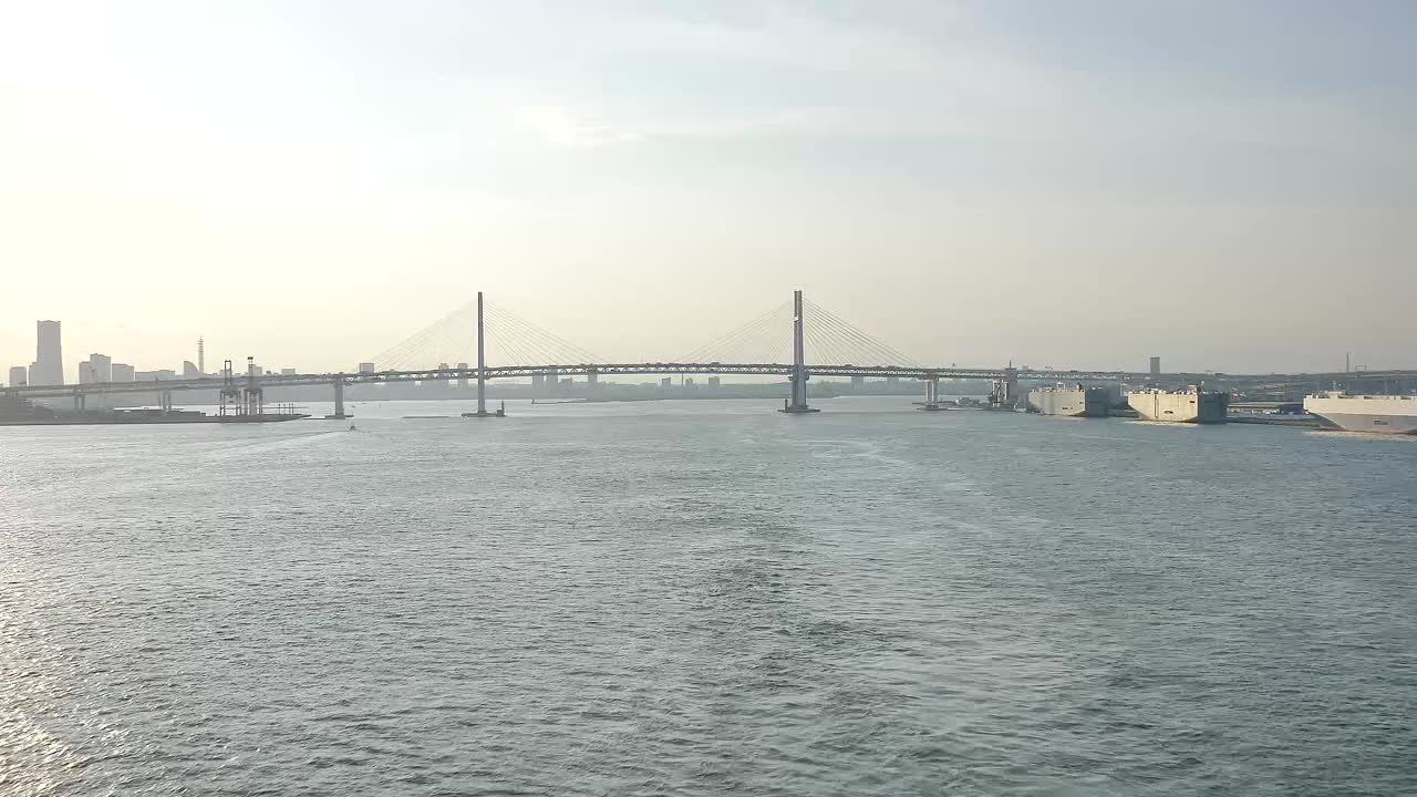 A wide shot of the Yokohama Bay Bridge taken from the cruise ship top deck, capturing ocean views and towering bridge spans