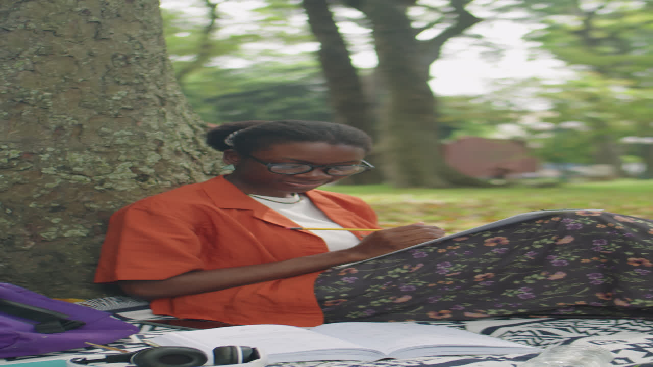 Black Female Student Doing Homework in Park