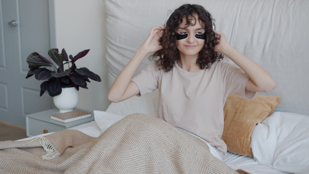 Woman Dancing in Bed with Headphones and Sleep Mask