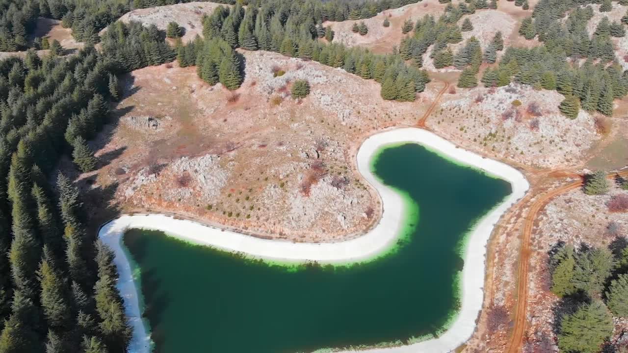 Drönarfilm från luften över Barouk-sjön i Libanon, en grön reservoar omgiven av skog och kullar. Idealisk för reseturism, natur, miljö och natursköna flygbakgrunder.