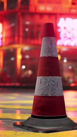 red and white traffic cone on a city street at night