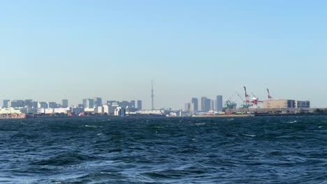 Skyline-Der-Stadt-Und-Industriehafen-über-Unruhiges-Blaues-Meer,-Klarer-Himmel-Gesehen