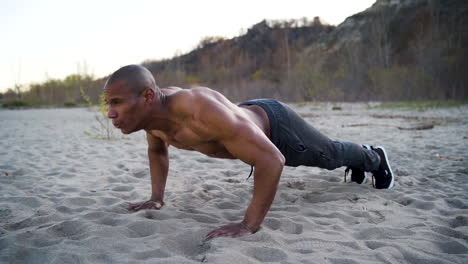hombre atractivo y atlético haciendo flexiones en la playa