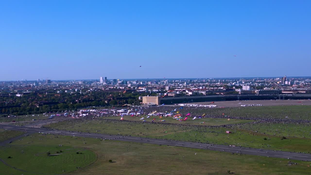 thousands of Berliners enjoying the giant kite festival on a sunny day at Tempelhofer Feld, the former Tempelhof Airport. Perfect aerial view flight overflight flyover drone