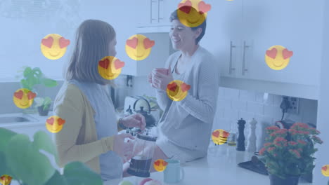 animación de emojis de corazón sobre una feliz pareja de mujeres caucásicas enamoradas bebiendo café.