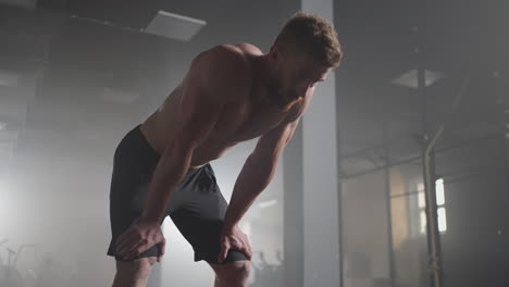 exhausted young men resting after intensive workout in gym. fitness healthy man tired after strength training exercise at gym. tired male fit model with standing and relaxing after intense workout.