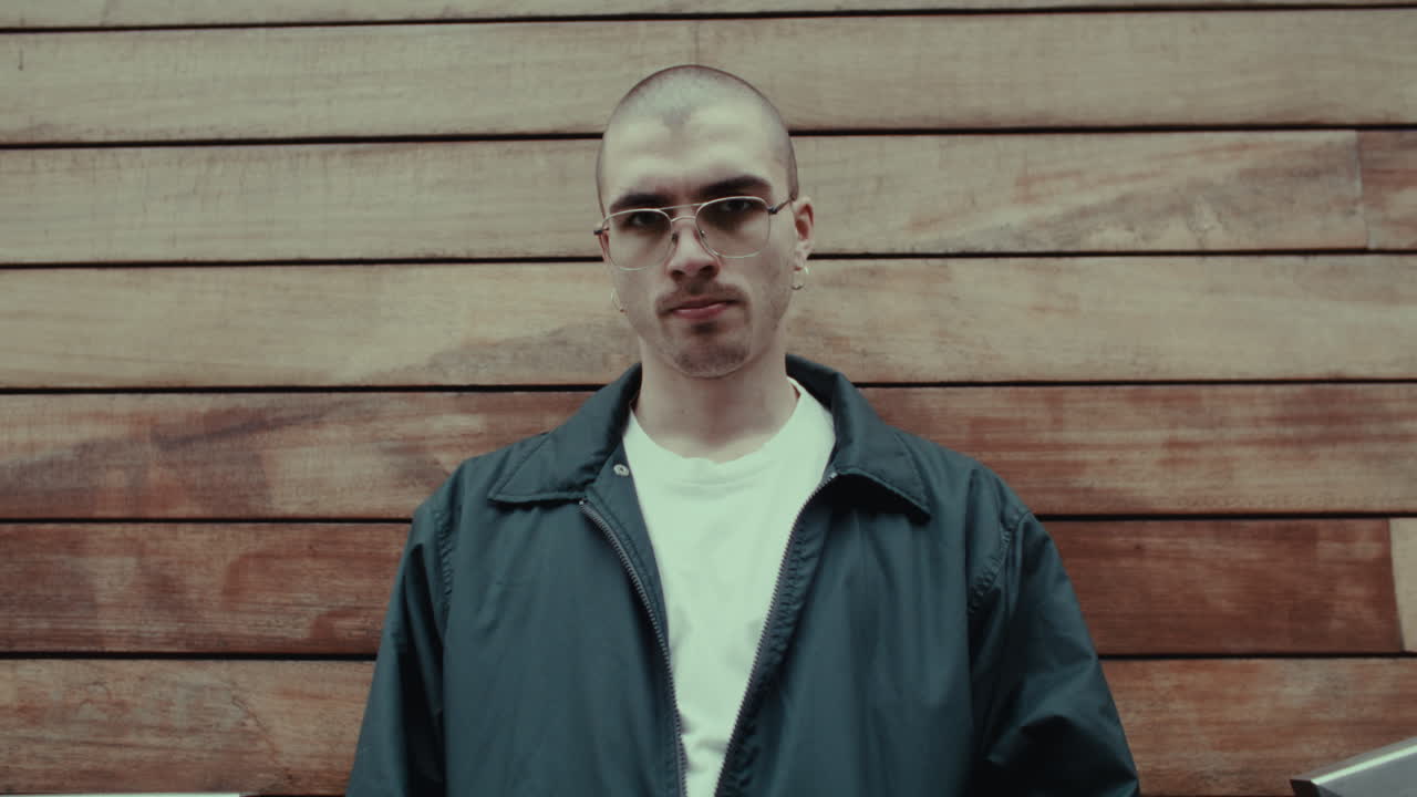 Man in casual attire against a wooden wall