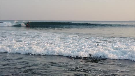 anonymous surfer on waves at little andaman island at sunset