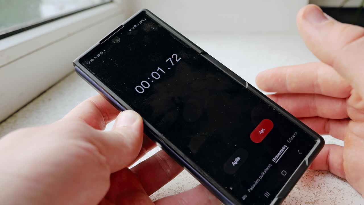 Indoor clip of man launching stopwatch on mobile phone, slow motion for detail
