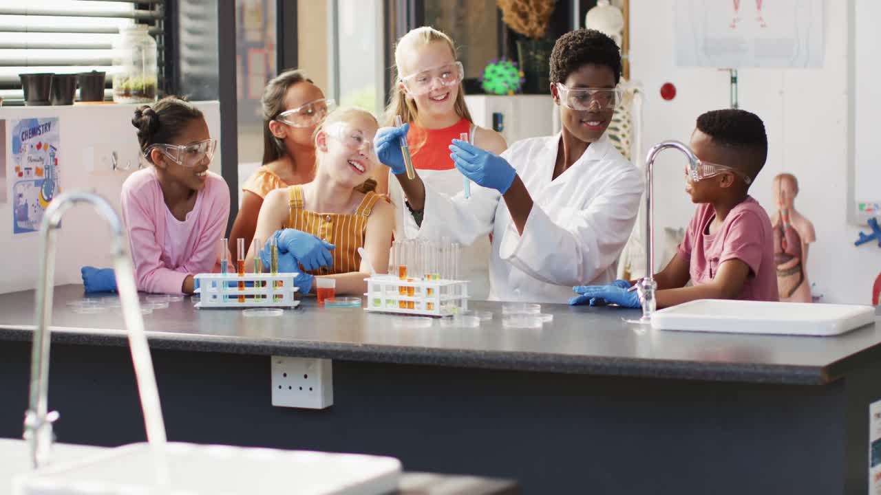 maestra diversa y escolares felices teniendo clase de ciencias en el laboratorio escolar