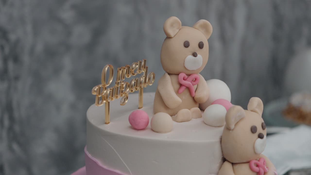 white cake with teddy bear fondant toppers and a golden baptism sign in Portuguese
