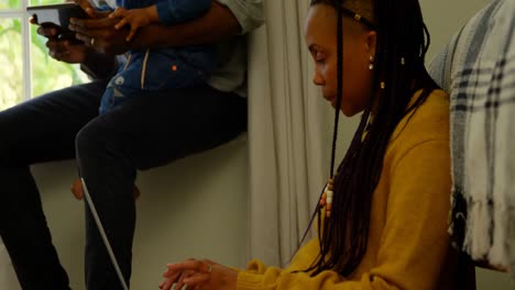 side view of young black mother using laptop and sitting on floor of comfortable home 4k