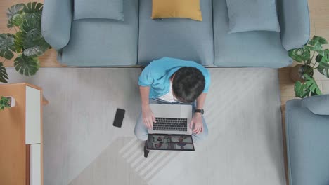 vista superior zoom out toma de un hombre agitando las manos mientras tiene una reunión en la computadora portátil en el suelo frente a un sofá en casa