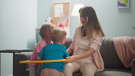 mother-plays-with-two-children-in-living-room,-they-laugh