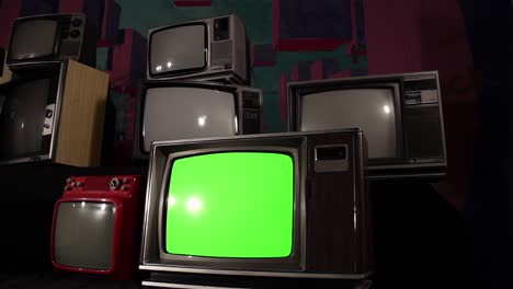 three old television sets with green screen on a retro tv wall. dolly shot. 4k resolution.