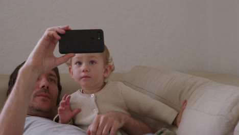 caucasian man looking smartphone with baby at home