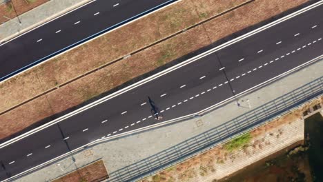 vista de drone de un hombre andando en bicicleta por la carretera, con sombras