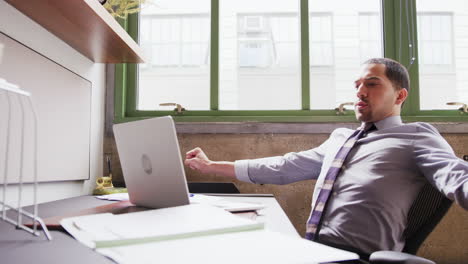 Tired-Hispanic-businessman-working-with-laptop-in-office