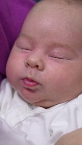 cute child sleeping sweetly and pressing his tiny lips in his sleep. adorable baby boy is resting peacefully in his mother's hands. close up. vertical video